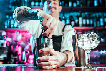 Image showing Expert barman is making cocktail at night club.