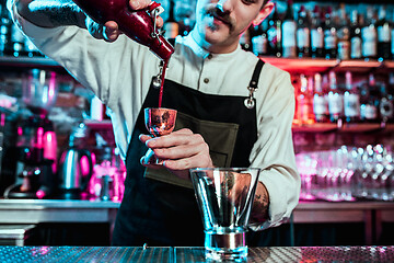 Image showing Expert barman is making cocktail at night club.