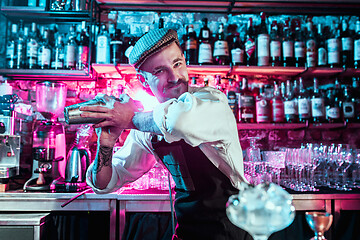 Image showing Expert barman is making cocktail at night club.