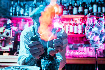 Image showing Expert barman is making cocktail at night club.