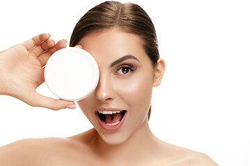 Image showing Cute girl preparing to start her day. She is applying moisturizer cream on face.