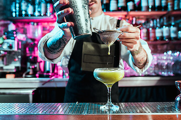 Image showing Expert barman is making cocktail at night club.