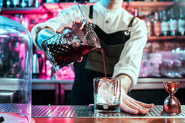 Image showing Expert barman is making cocktail at night club.