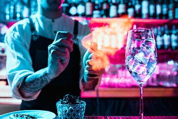 Image showing Expert barman is making cocktail at night club.