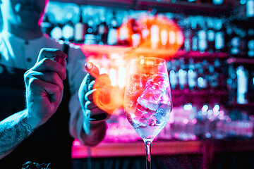 Image showing Expert barman is making cocktail at night club.