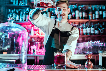 Image showing Expert barman is making cocktail at night club.