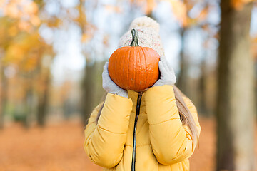 Image showing girl hiding her face behind pumpkin at autumn park