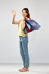 Image showing happy asian woman with shopping bags waving hand