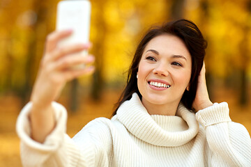 Image showing woman taking selfie by smartphone at autumn park