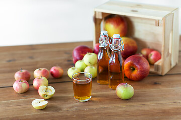 Image showing glass and bottles of apple juice on wooden table
