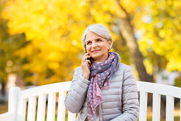 Image showing senior woman calling on smartphone at autumn park