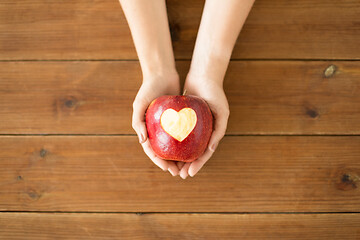 Image showing close up of hands holding apple with carved heart