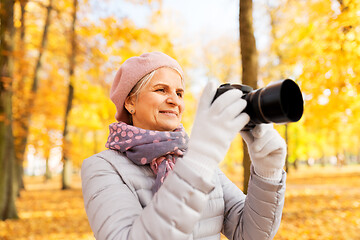 Image showing senior woman with photo camera at autumn park