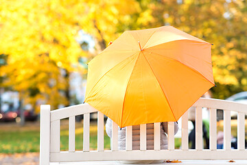 Image showing woman with umbrella sits on bench in autumn park