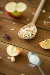 Image showing oatmeal in wooden spoon, cut apples and nuts