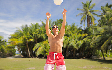 Image showing young man with ball playing volleyball on beach