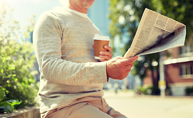 Image showing senior man with coffee reading newspaper outdoors