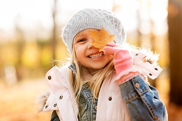 Image showing happy little girl with maple leaf at autumn park