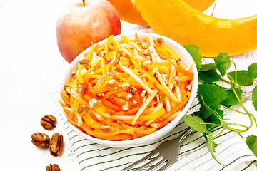 Image showing Salad of pumpkin and apple with nuts in bowl on light board