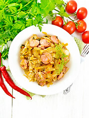 Image showing Cabbage stew with sausages in white plate on board top