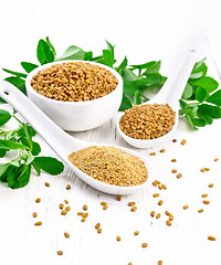 Image showing Fenugreek in two spoons and bowl with leaves on wooden board