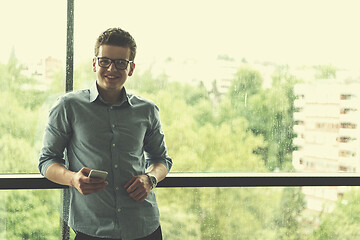 Image showing Businessman Standing In A Modern Building Near The Window With P