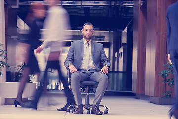 Image showing business man sitting in office chair, people group  passing by