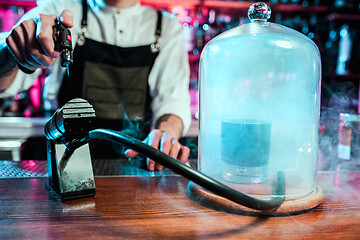 Image showing Expert barman is making cocktail at night club.