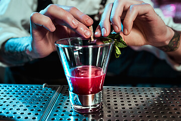 Image showing Expert barman is making cocktail at night club.