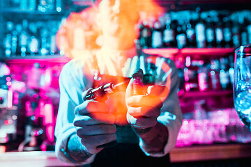 Image showing Expert barman is making cocktail at night club.