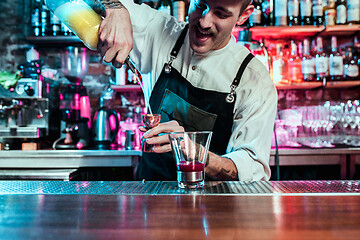 Image showing Expert barman is making cocktail at night club.