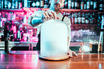 Image showing Expert barman is making cocktail at night club.