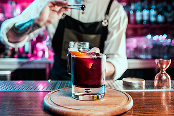 Image showing Expert barman is making cocktail at night club.