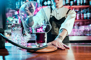 Image showing Expert barman is making cocktail at night club.