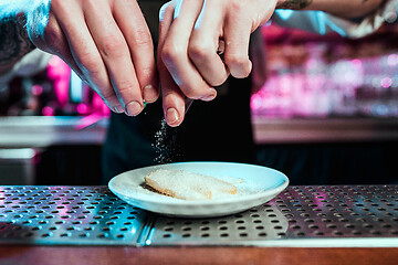 Image showing Expert barman is making cocktail at night club.