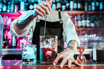 Image showing Expert barman is making cocktail at night club.