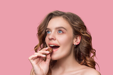 Image showing beauty portrait of a cute girl in act to eat a chocolate candy