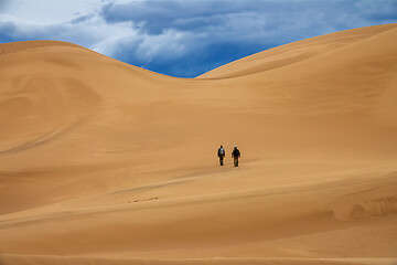 Image showing Travelers in desert dunes in mountains