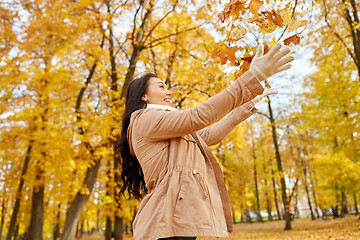 Image showing happy woman having fun with leaves in autumn park