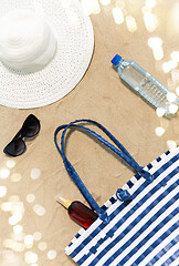 Image showing beach bag, sunscreen, sunglasses and hat on sand