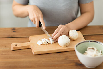 Image showing woman cutting champignons by knife on board