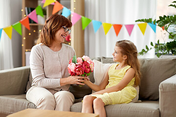 Image showing granddaughter giving grandmother flowers at home