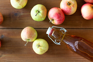 Image showing bottle of apple juice or vinegar on wooden table