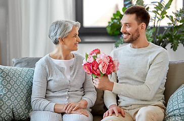 Image showing adult son giving flowers to senior mother at home