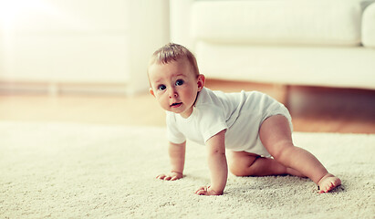 Image showing little baby in diaper crawling on floor at home