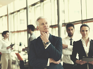 Image showing portrait of senior businessman as leader  with staff in backgrou