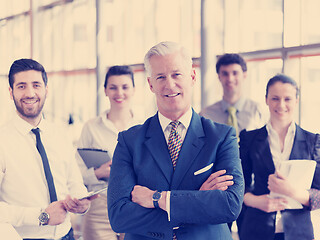 Image showing portrait of senior businessman as leader  with staff in backgrou