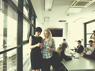 Image showing Two Elegant Women Using Mobile Phone by window in office buildin