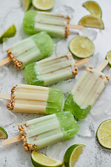 Image showing Lime and cream homemade popsicles or ice creams placed with ice cubes on gray stone backdrop