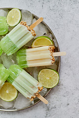 Image showing Summer refreshing homemade lime popsicles with chipped ice over stone background